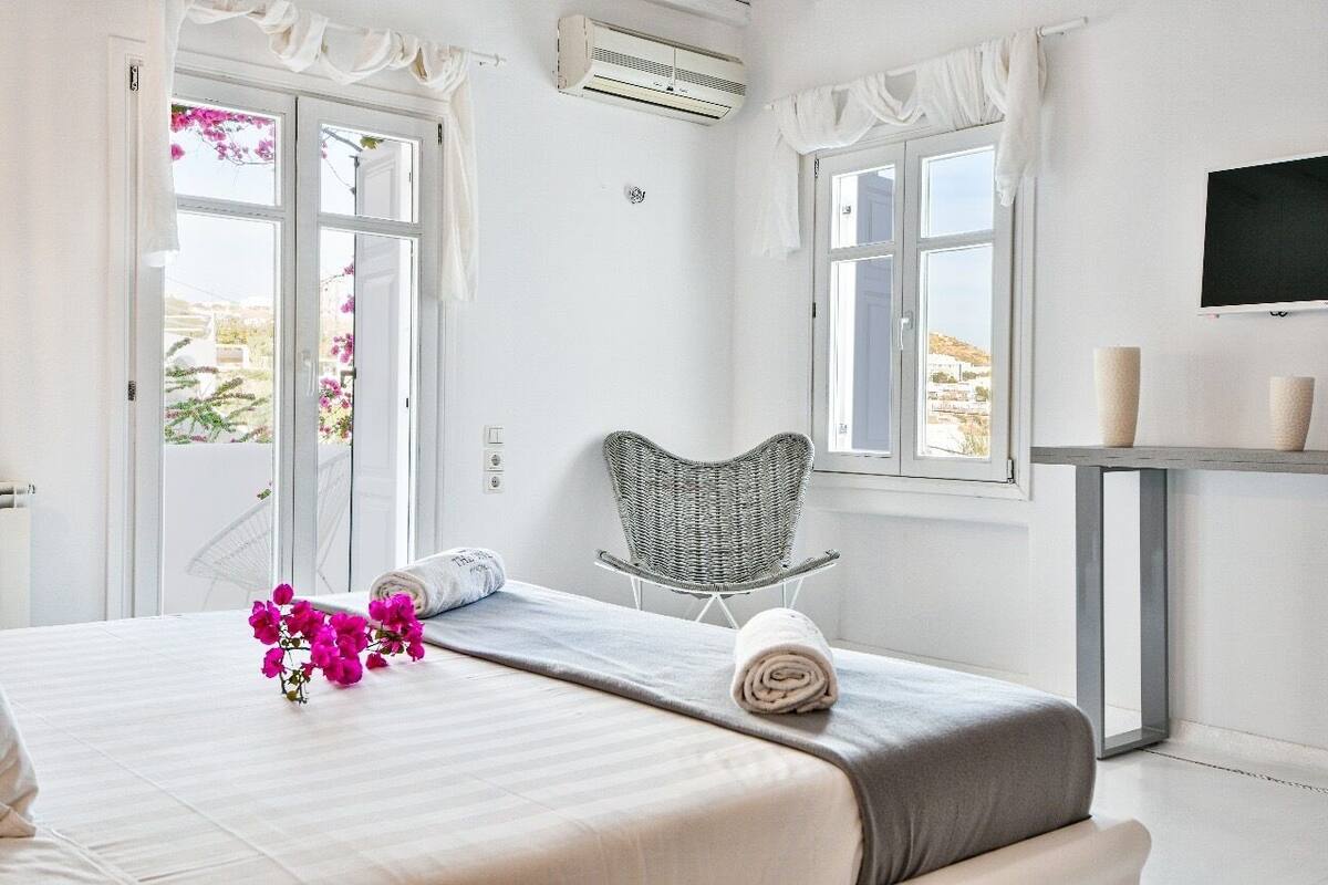 A hotel room with a bed, a chair, a TV, and a window with curtains.