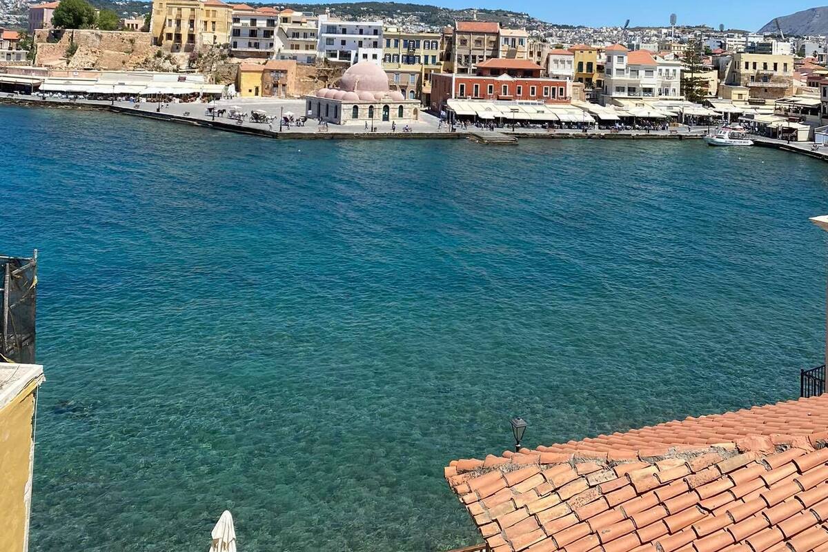 A coastal town with buildings along the waterfront, clear blue water, and a view of the sea.