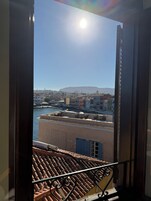 Vista desde un balcón con vistas a un paisaje urbano que incluye una masa de agua, edificios y una montaña distante.