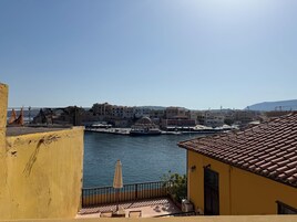 Μια παραθαλάσσια πόλη με κτίρια που βρίσκονται κατά μήκος της προκυμαίας, με καθαρό ουρανό και θέα στη θάλασσα.