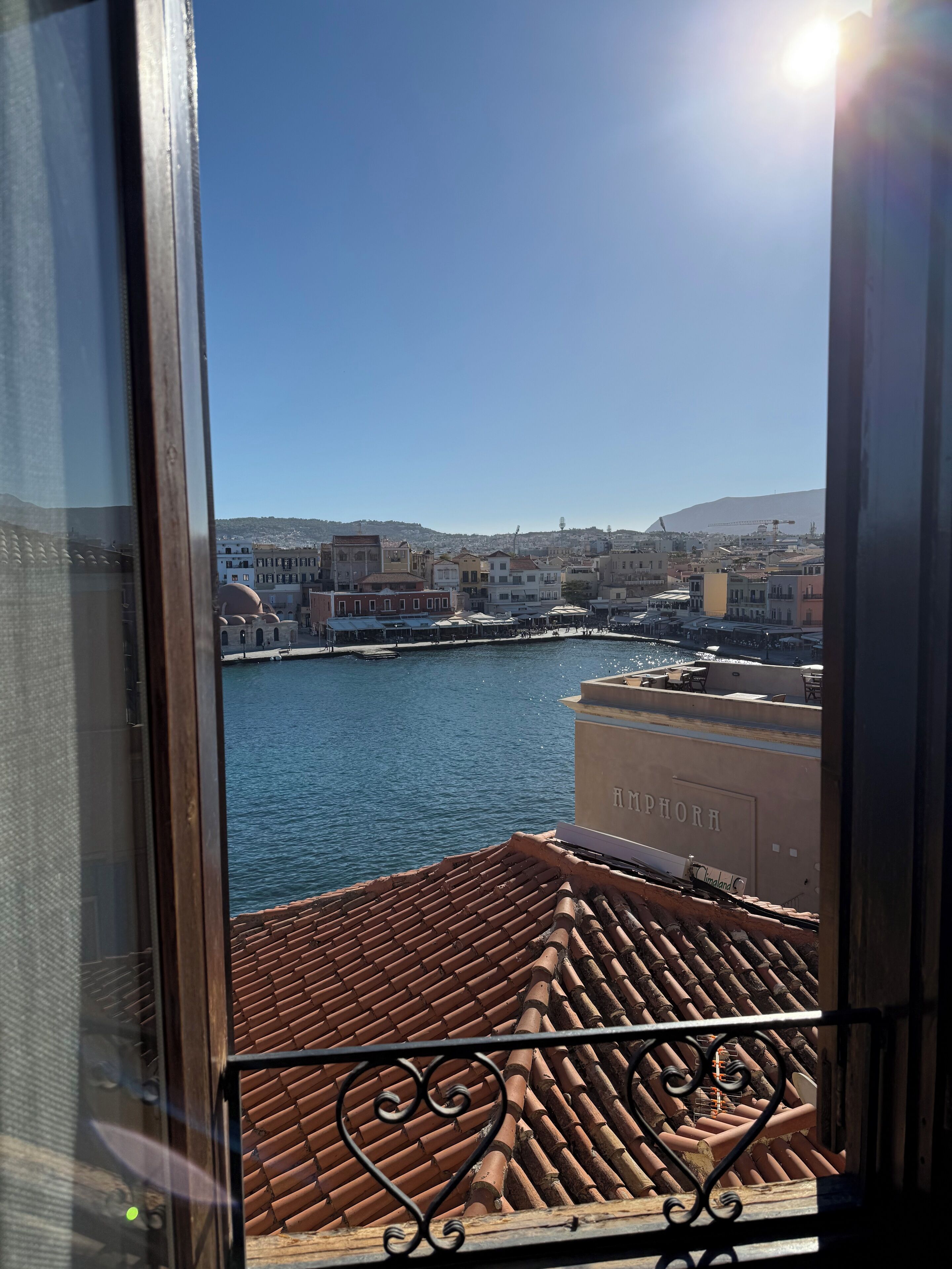 A view from a window overlooking a harbor with buildings and a clear sky.