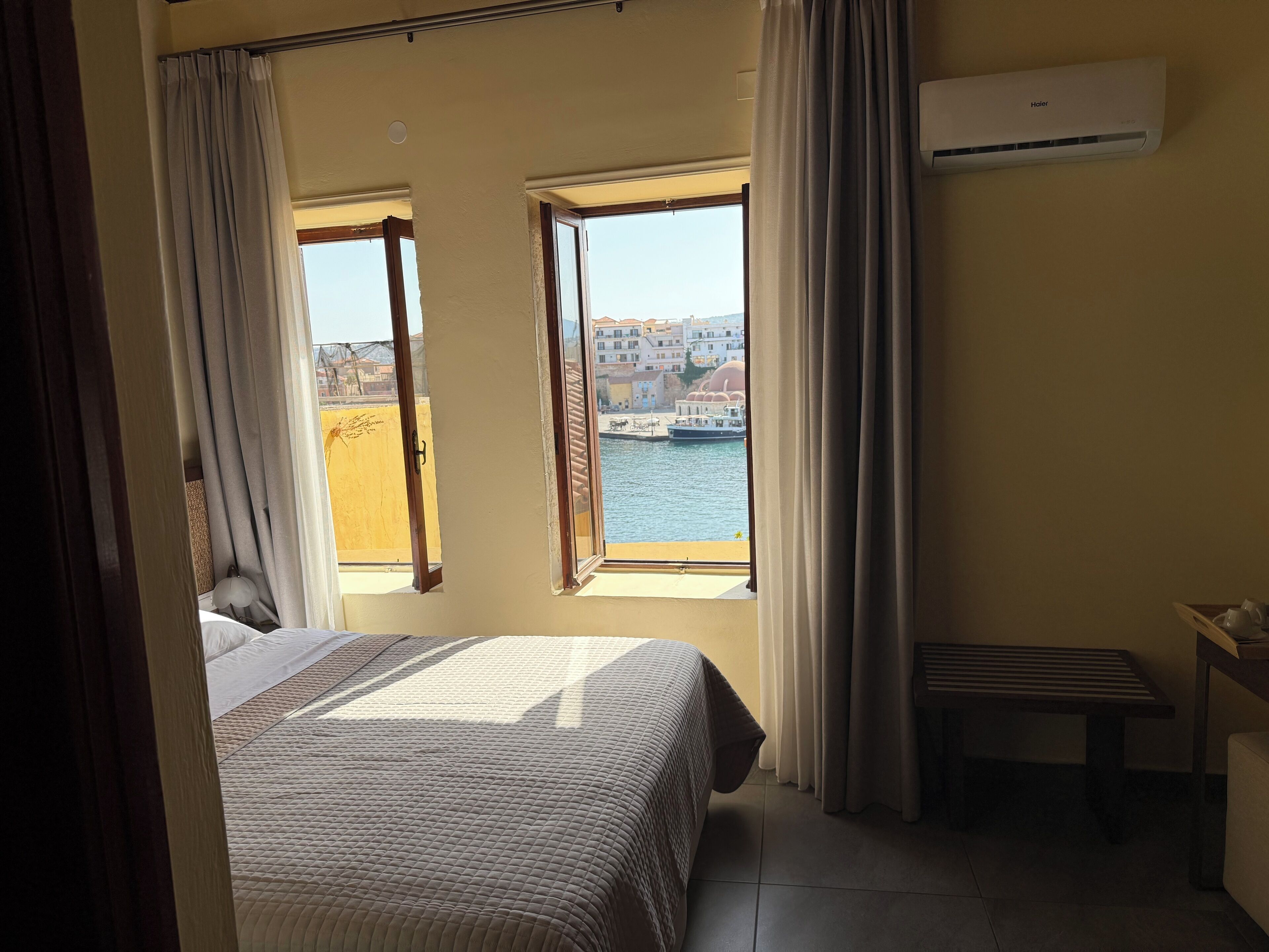 Una camera da letto con un letto, una finestra con tende, un comodino e un condizionatore d'aria.