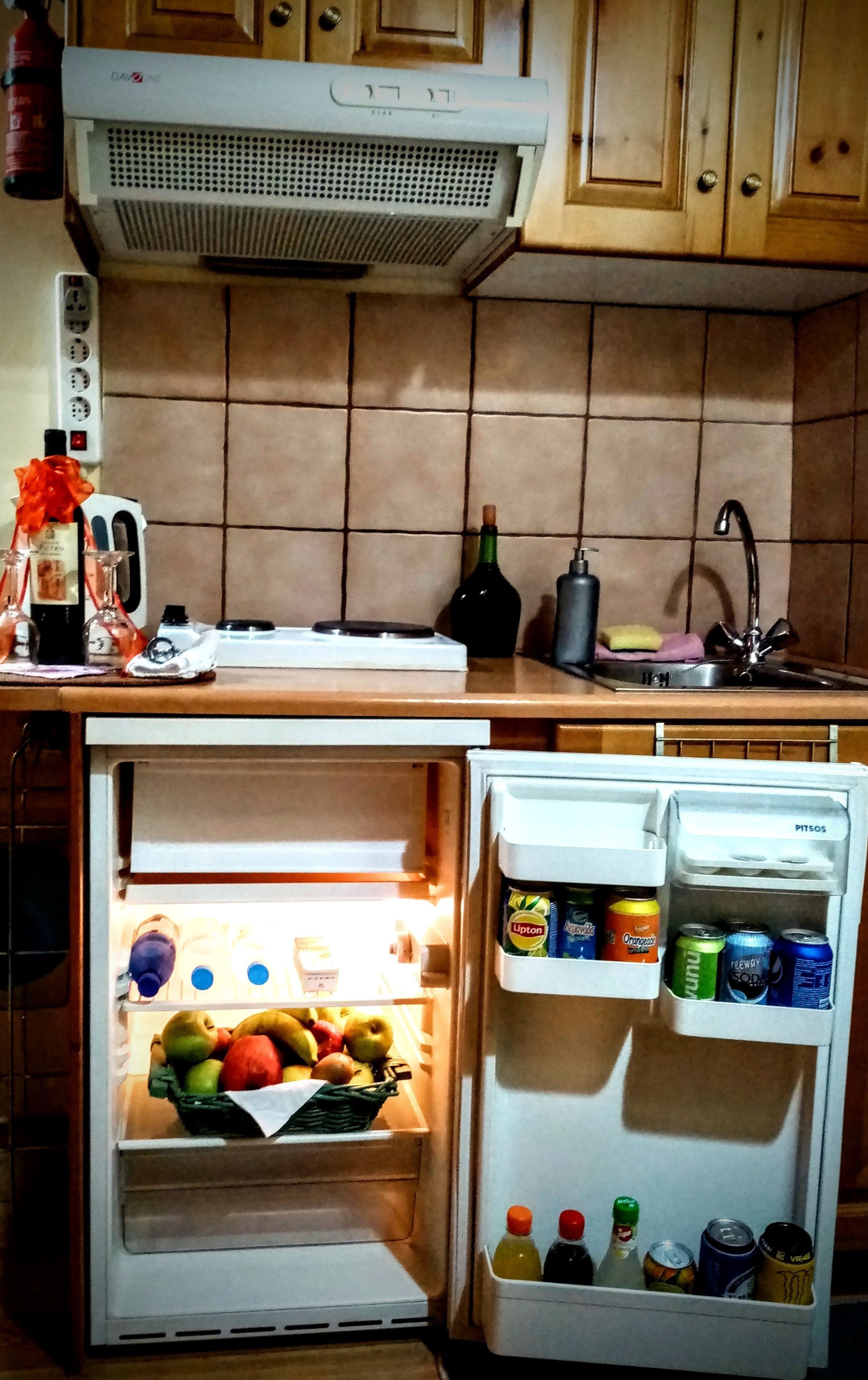 A kitchen with a built-in refrigerator containing fruits and beverages.