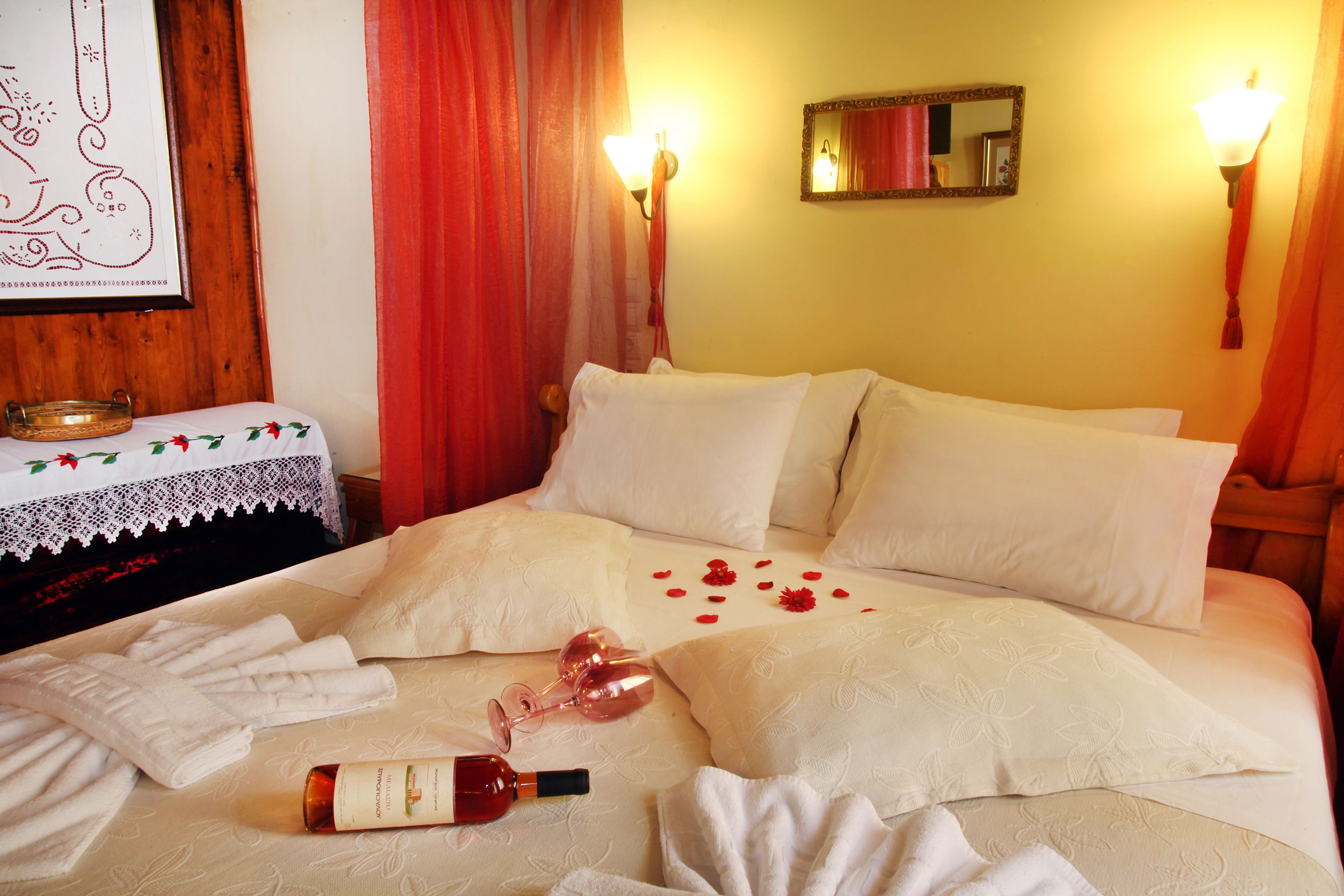 A hotel room with a neatly made bed, a bedside table with a lamp, and a mirror on the wall.