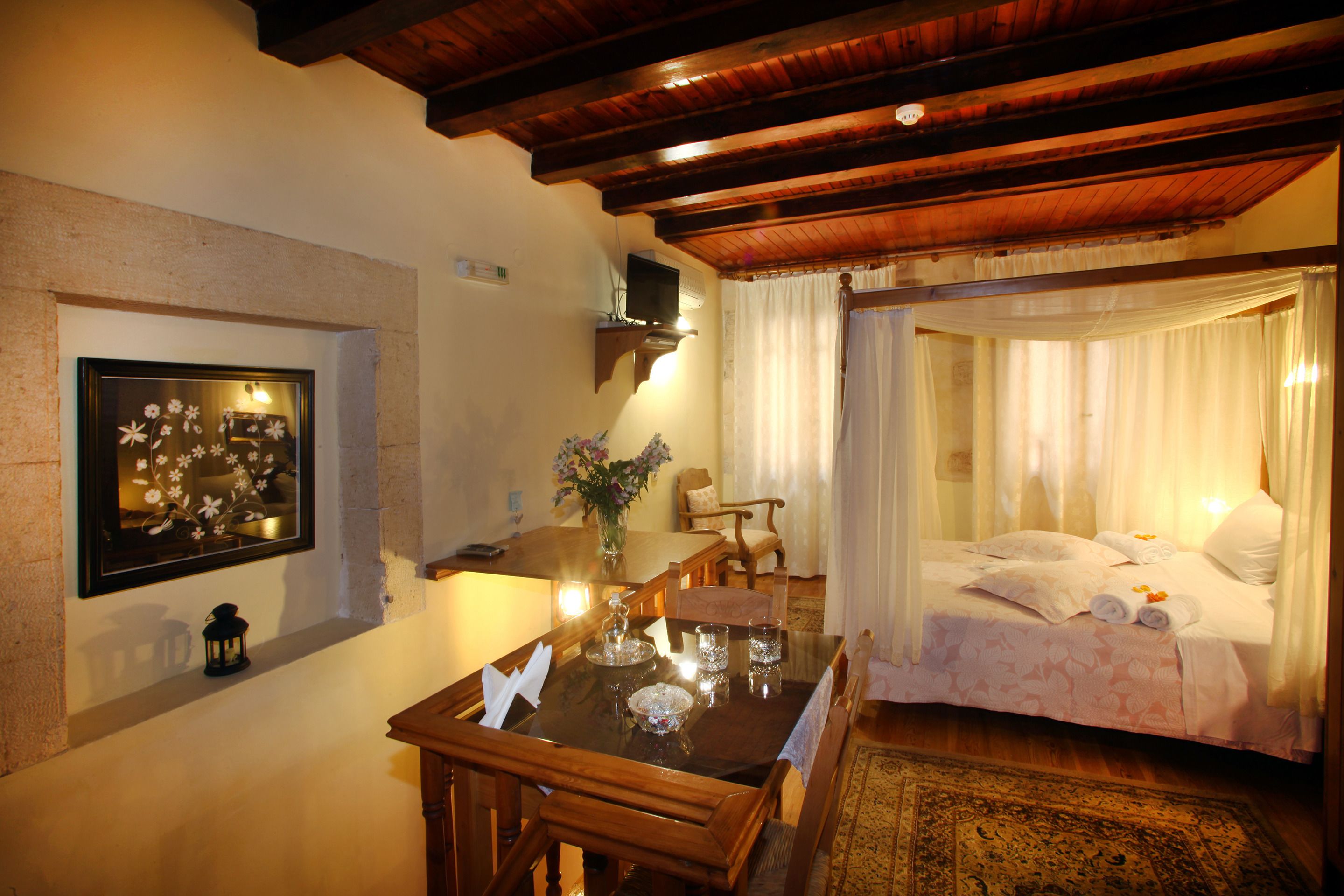 A cozy room with a wooden dining table, a bed with white bedding, and a decorative mirror on the wall.