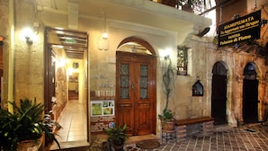 L’entrée d’un bâtiment historique, avec une porte en bois, des plantes en pot et une enseigne indiquant le nom et l’adresse.