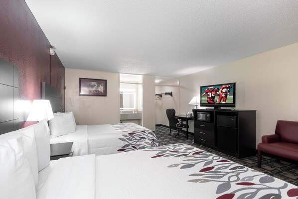 A hotel room with two beds, a television, a desk, and a chair.