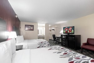 Habitación de hotel con dos camas, televisión, escritorio y una silla.