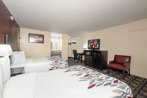 A hotel room with two beds, a desk, a television, and a red chair. - Red Roof Inn Murray (Murray)