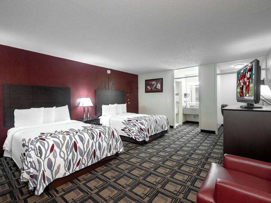 A hotel room with two beds, a TV, a desk, and a chair.