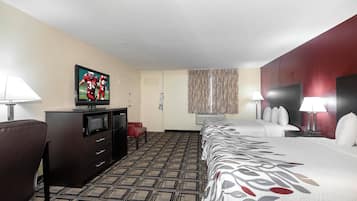 A hotel room with a bed, a TV, a desk, a chair, a lamp, and a patterned carpet.