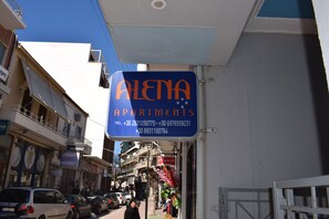 An exterior view of a building with a sign for 'ALETNA APARTMENTS' and contact numbers.