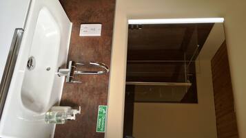 Ein Badezimmer mit Waschbecken, einer Handseifen-Spender und einem Schild, das eine Trinkwasseranlage kennzeichnet.