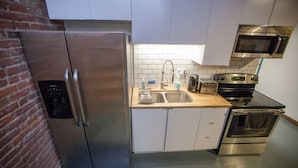 Eine kleine Küche mit einem Edelstahl-Kühlschrank, einer Mikrowelle, einem Toaster und einem Backofen.