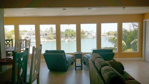 A living room with a view of a marina, a dining area with chairs, and a sofa.