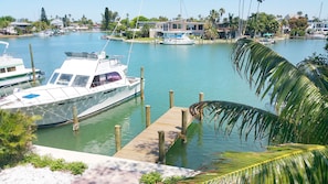 A marina with boats docked, a wooden dock, and a residential area with houses in the background.
