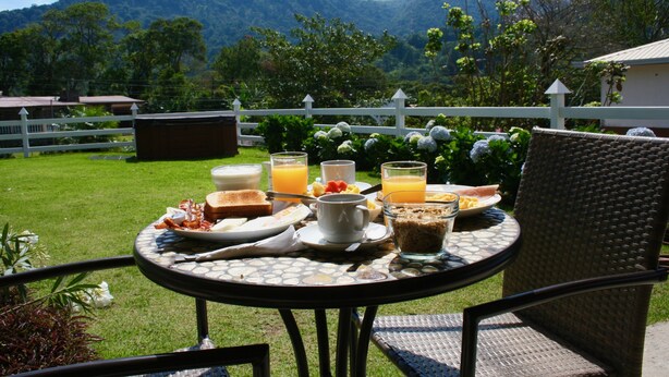 Una mesa de desayuno al aire libre con una vista panorámica de las montañas al fondo.