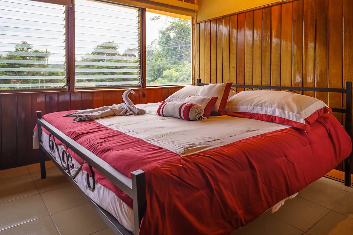 A bed with a red and white bedspread, a swan pillow, and a swan decoration.