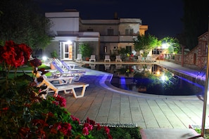 A pool area with lounge chairs and a modern house in the background. - Hotel Dimitra Sun (Rhodes)