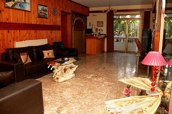A living room with a wooden wall, a sofa, a coffee table, and a lamp. - Hotel Dimitra Sun (Rhodes)