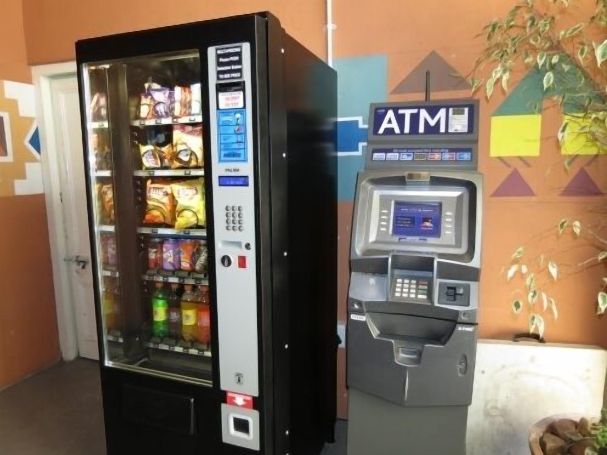 A vending machine with snacks and a separate ATM machine.