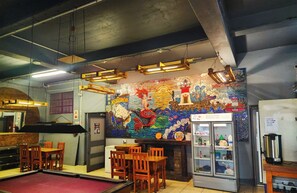 A pool table, wooden chairs, a mural, a refrigerator, and a sign about the ice maker. - Riverlodge Backpackers (Cape Town)