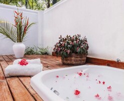 A spa area with a hot tub, towels, and potted plants.