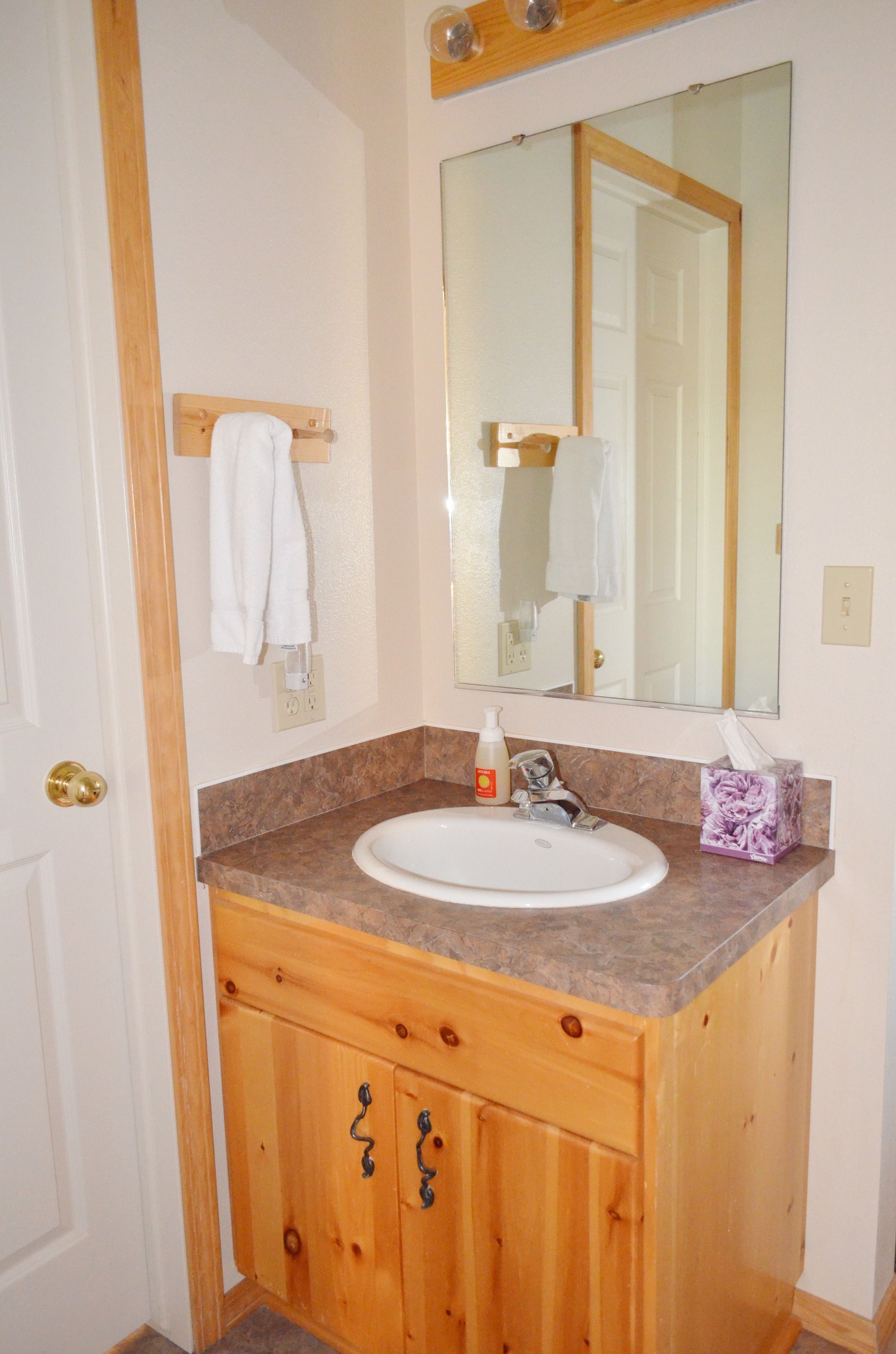 A bathroom with a wooden vanity, white sink, and a large mirror.