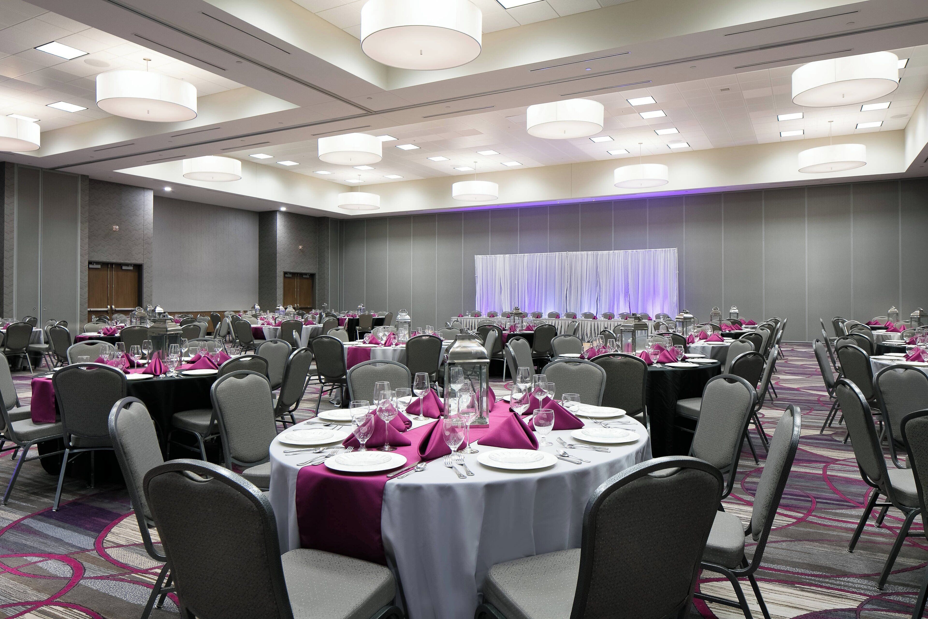 A banquet hall with round tables set for dining, equipped with chairs and table settings.