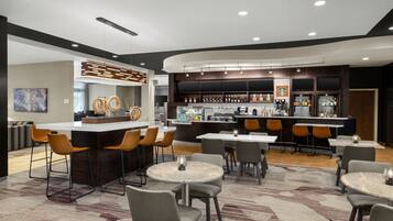 Relax in our stylish lobby, featuring a central bar with a selection of drinks and a coffee machine, alongside comfortable seating areas.