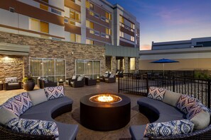 A courtyard with a fire pit, outdoor seating, and a view of a multi-story building. - Courtyard by Marriott Omaha Bellevue Beardmore Event Center (Bellevue)