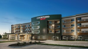 Un hotel Courtyard Marriott con un diseño moderno, varios pisos y una entrada bien iluminada.