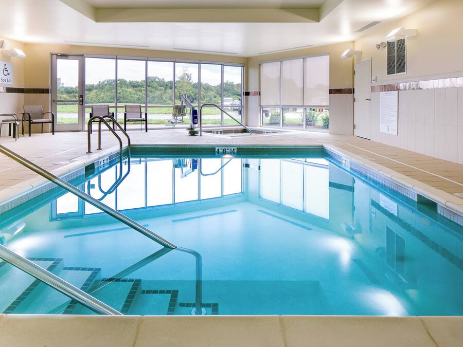 A large indoor swimming pool with clear glass walls, a spa lift, and a view of the outdoors.