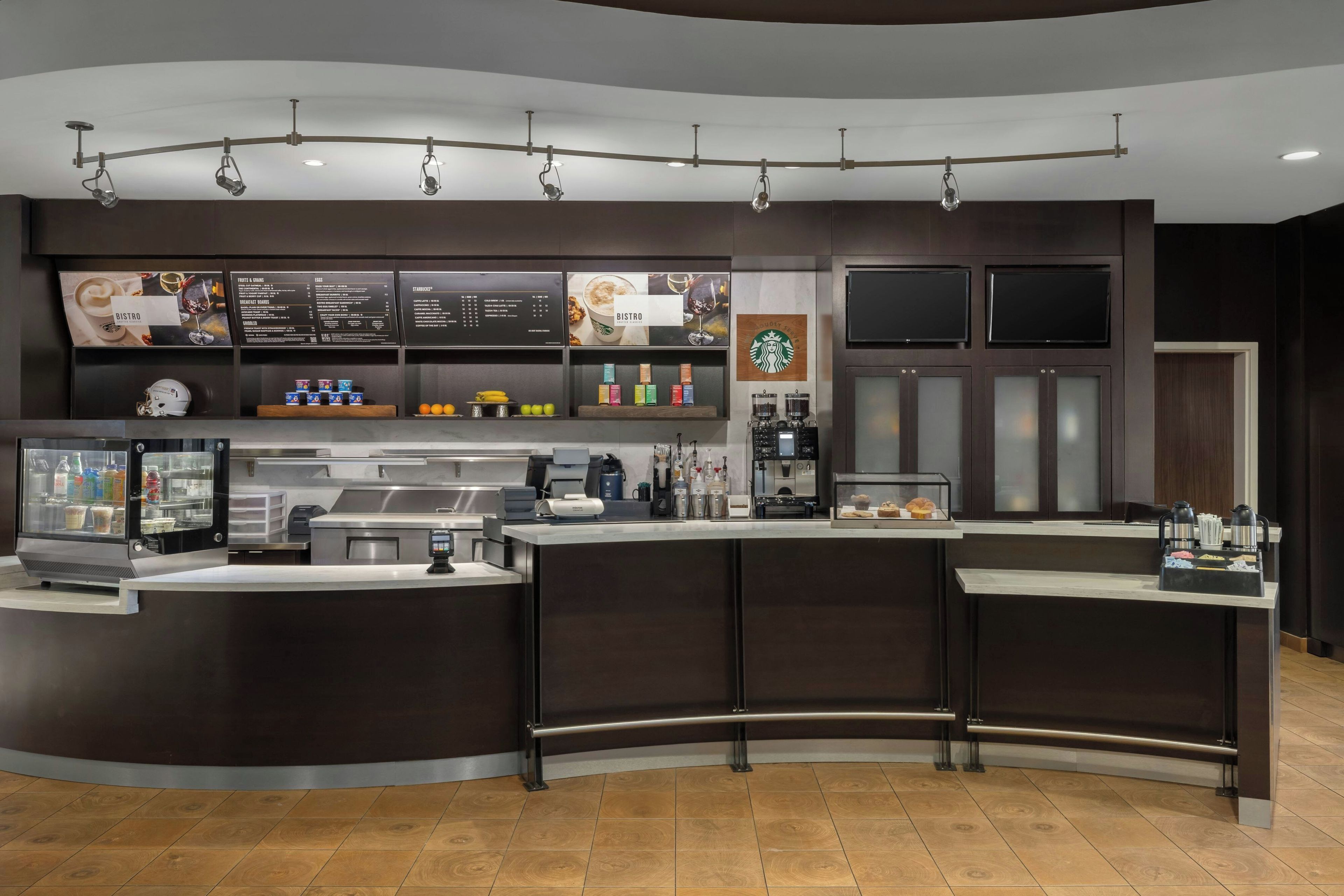 Un café moderne avec un comptoir incurvé, des machines à expresso et un tableau affichant le menu.