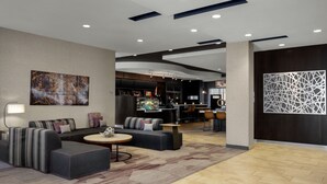 Un moderno vestíbulo de hotel con zona de estar, bar y comedor.