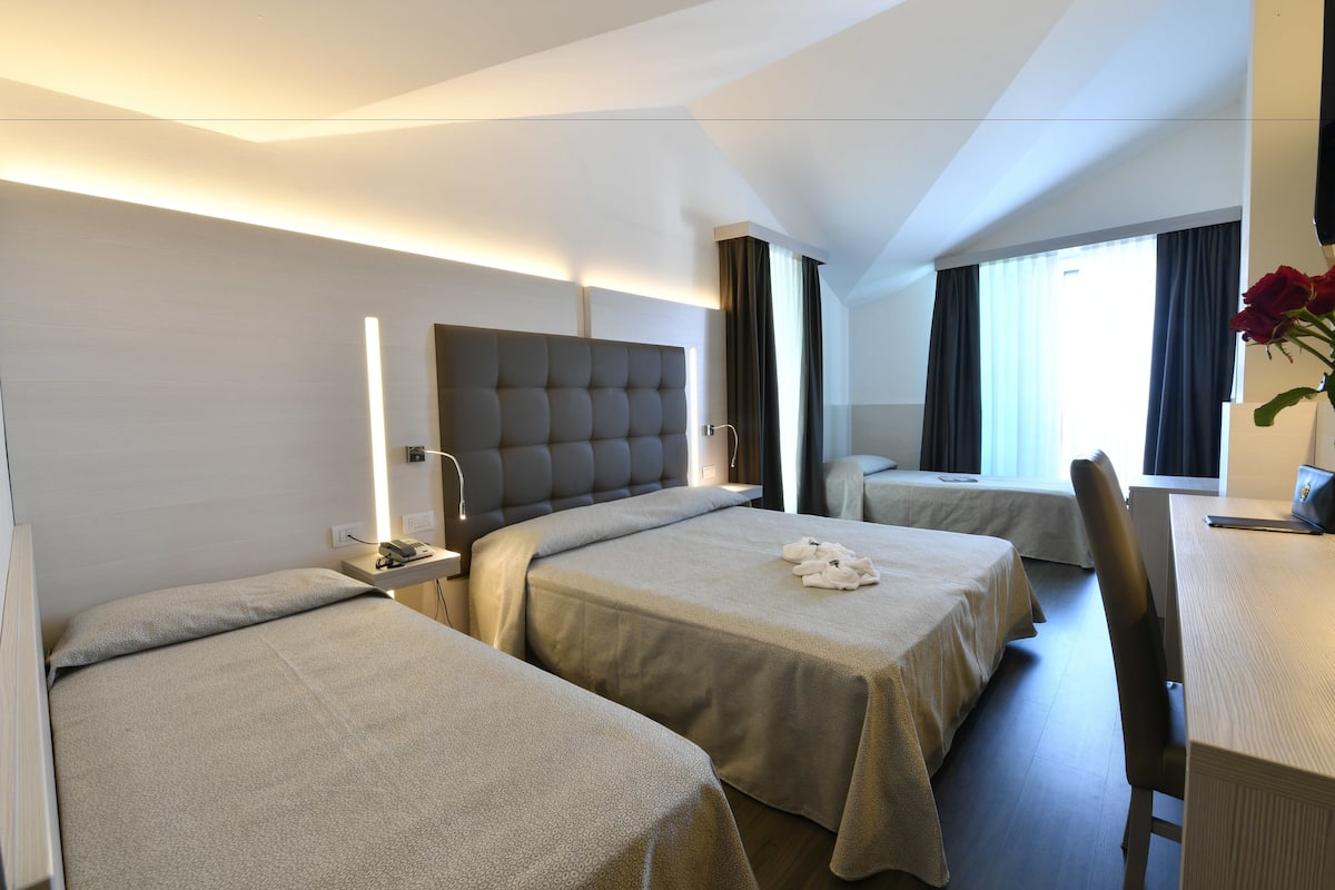 A hotel room with two beds, a desk, and a chair.