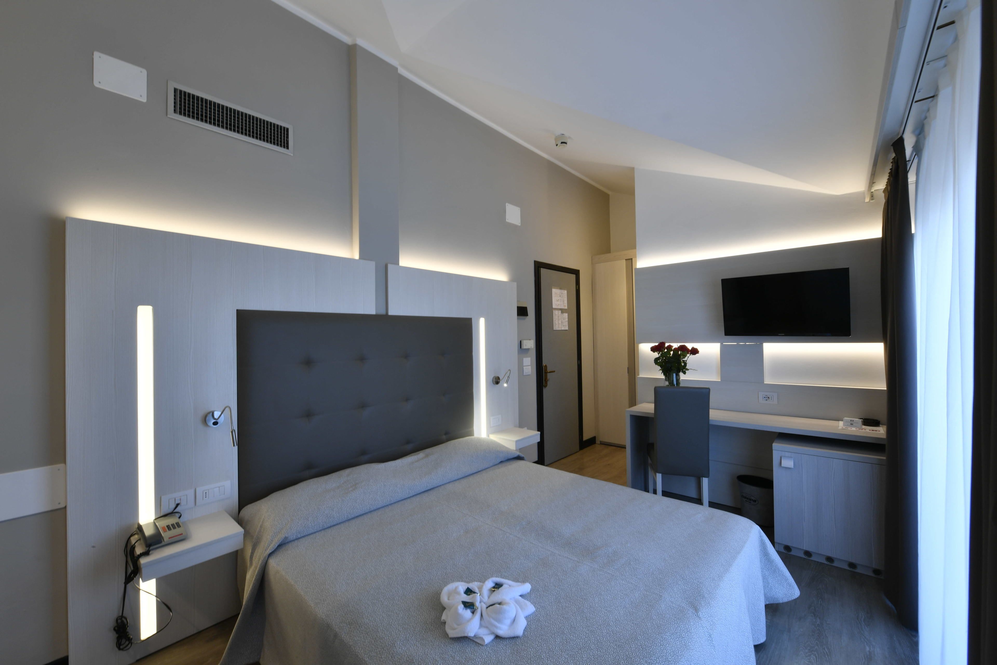 Une chambre d’hôtel moderne avec un grand lit, une table de chevet et un espace bureau.