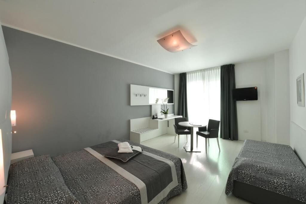 A modern hotel room with two beds, a desk, and a TV.