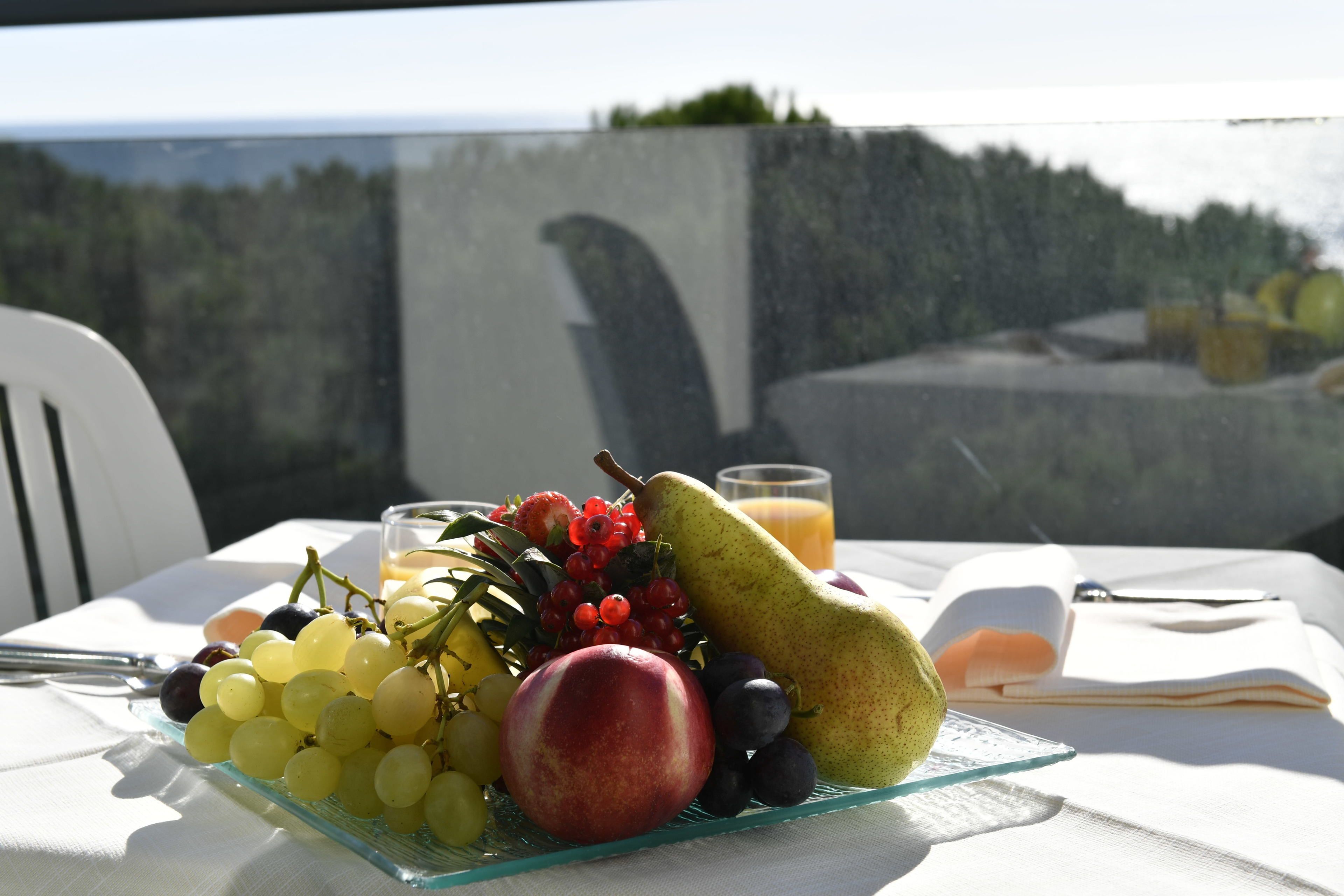 Uma mesa com um prato de frutas, um copo de suco e um livro.