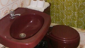 A bathroom with a red sink, a toilet, and a shower curtain with a floral pattern. - El Dorado Residencial (Lima)