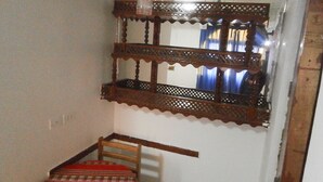 A corner with a wooden chair and a mirror with a decorative frame. - El Dorado Residencial (Lima)