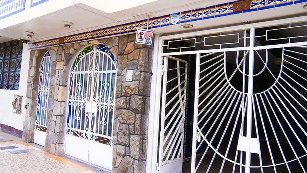 A building with a stone facade, two large metal gates with intricate designs, and a sign indicating a no entry for vehicles. - El Dorado Residencial (Lima)