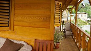 A wooden deck with a sofa and potted plants. - C & K Apartments (Castara)