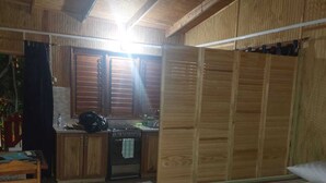 A room with a bed, a small kitchenette, and a wooden ceiling. - C & K Apartments (Castara)