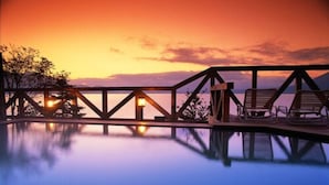 A serene pool area with a sunset view, wooden deck, and lounge chairs. - Sapporo’s Secret Onsen Sanctuary Marukoma Onsen Ryokan (Chitose)
