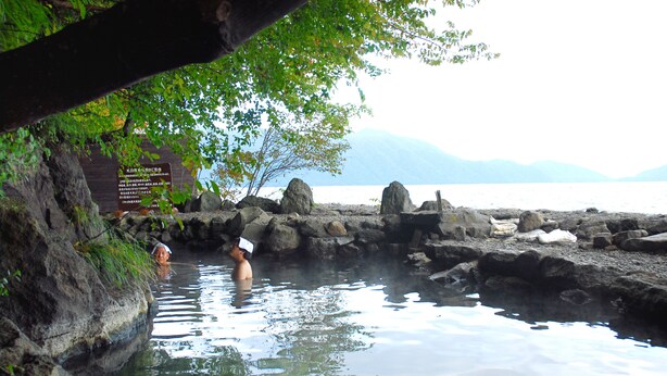 A natural hot spring with rocky surroundings and a body of water. - Sapporo’s Secret Onsen Sanctuary Marukoma Onsen Ryokan (Chitose)