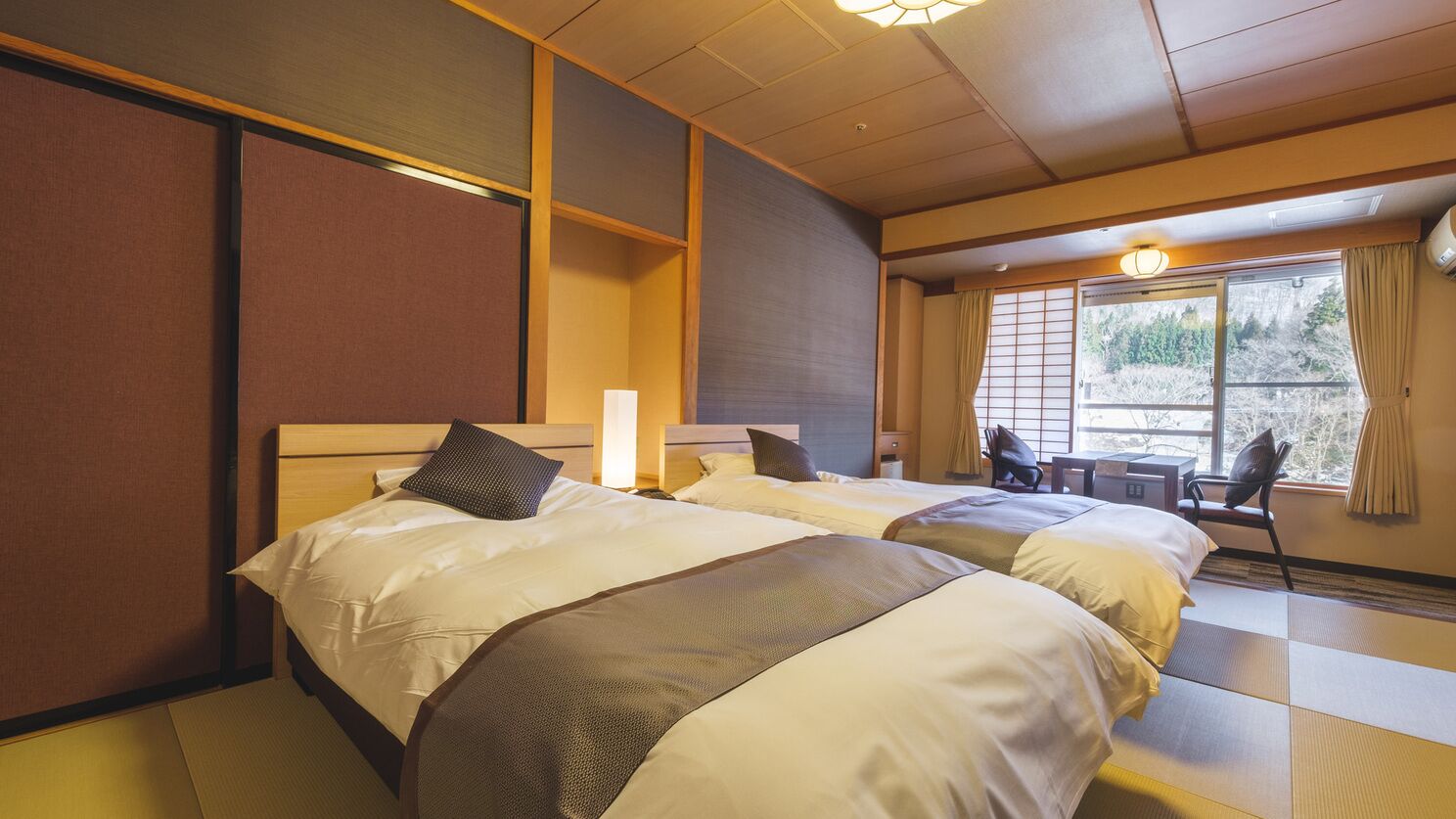 Habitación de hotel con dos camas, un escritorio y una ventana con cortinas.