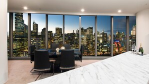 Un comedor moderno con vistas a la ciudad, una mesa de mármol y sillas negras.