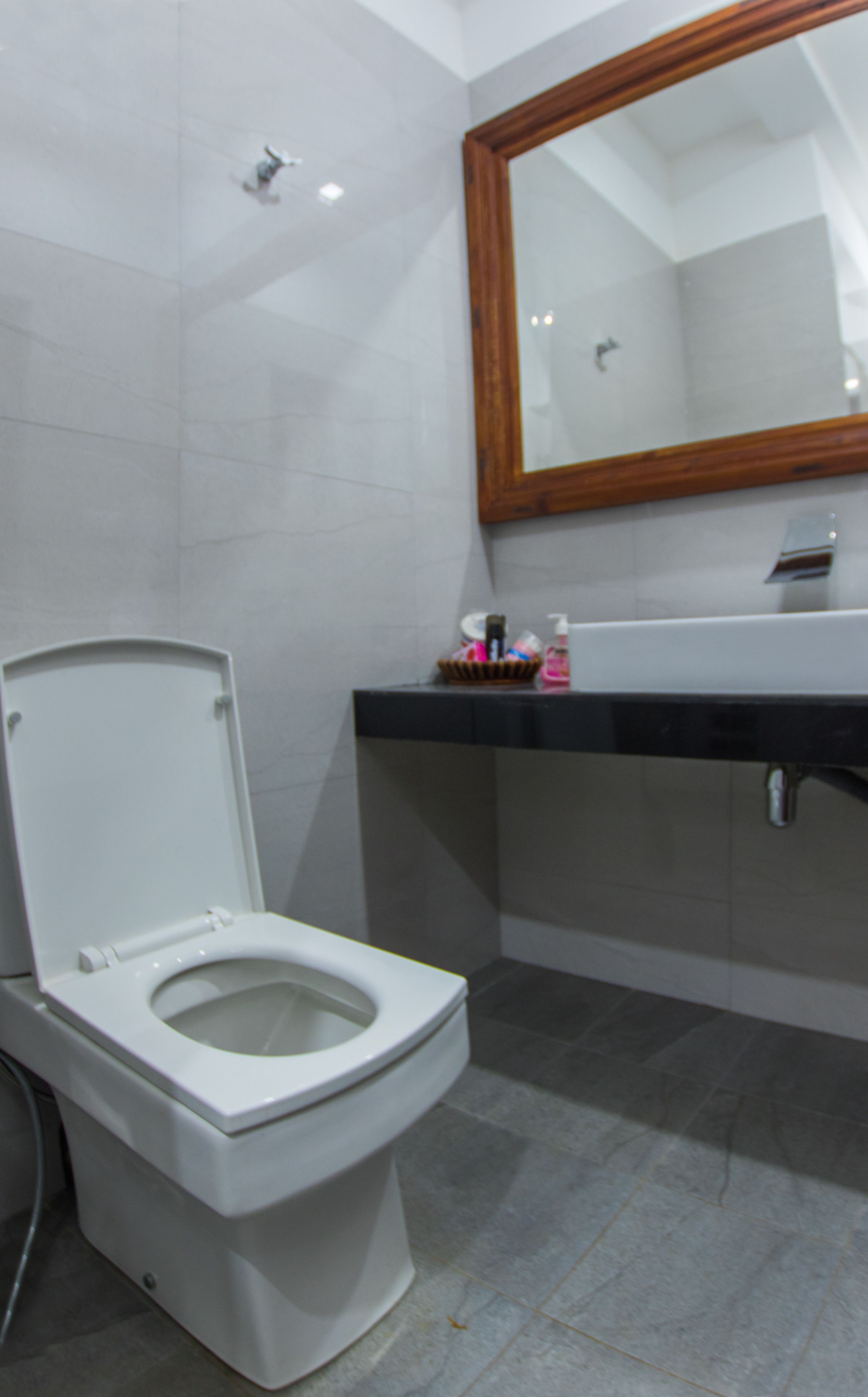 A modern bathroom with a white toilet, a sink with a mirror above it, and a shower area.