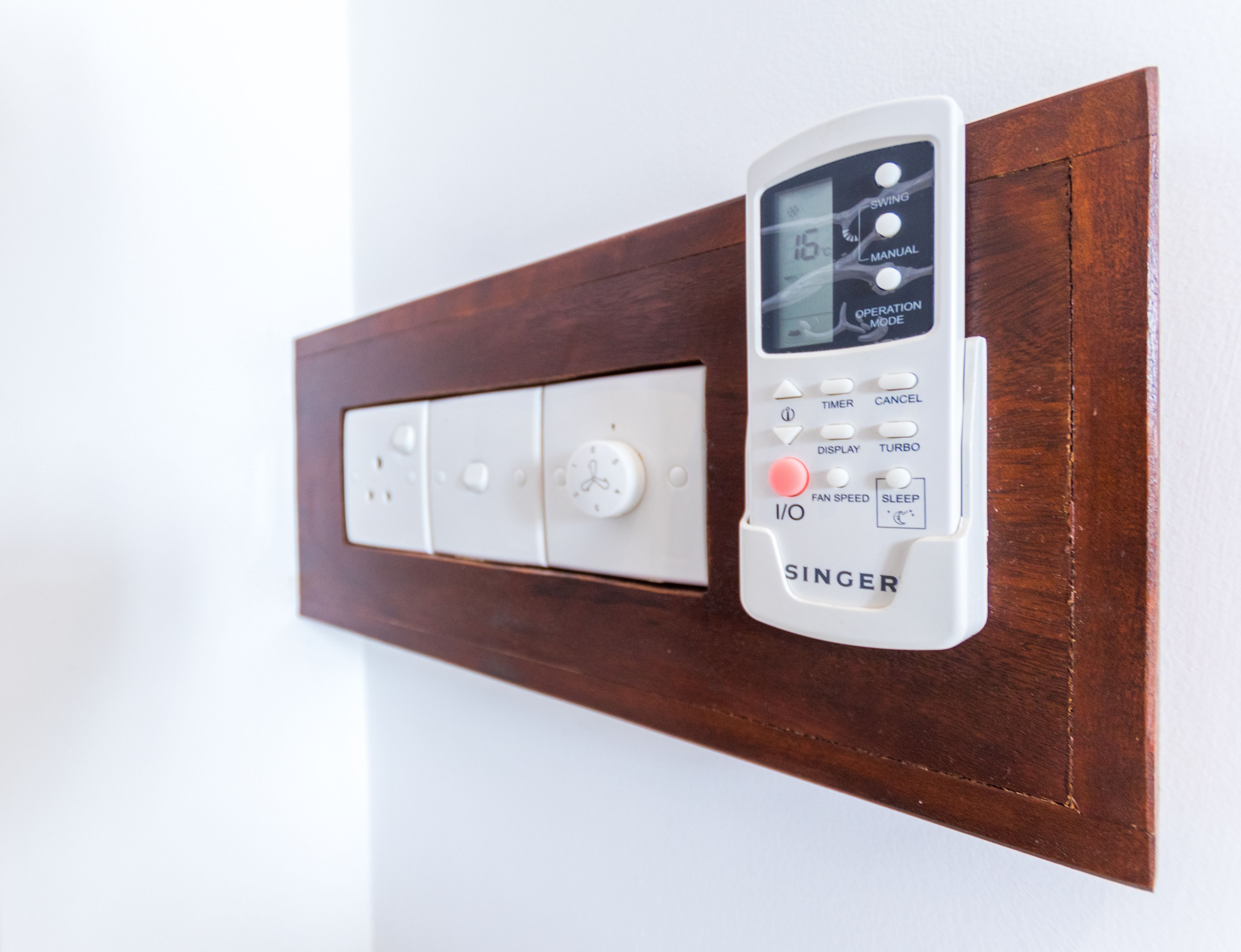Een bedieningspaneel aan de muur met een timer, ventilatorsnelheid en slaapstand.